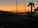 Sunset view of the Las Vegas skyline from the neighborhood street with palm tree and residential houses at 114 Tamarack Dr, Henderson, NV 89002