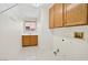 Tiled laundry room features upper cabinets, sink with window, and washer/dryer hookups at 114 Tamarack Dr, Henderson, NV 89002