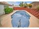 Swimming pool with ladders and railings, surrounded by landscaping and a red brick wall at 114 Tamarack Dr, Henderson, NV 89002