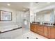 Bright bathroom featuring a tub, glass shower, wood vanity, and a large framed mirror at 135 E Harmon Ave # 1703, Las Vegas, NV 89109