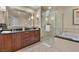 Bathroom featuring granite counters, wood cabinetry, and soaking tub with a glass enclosed shower at 135 E Harmon Ave # 407, Las Vegas, NV 89109