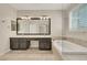 Luxurious main bathroom featuring a soaking tub, dual sinks, custom cabinets and shuttered windows at 2262 Alanhurst Dr, Henderson, NV 89052