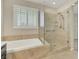Modern bathroom featuring a soaking tub with tile surround and glass walk-in shower with handrails at 2262 Alanhurst Dr, Henderson, NV 89052