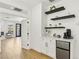 Bright coffee bar area with white cabinets, sleek countertop, floating shelves and mini fridge in a modern home at 2469 Sun Reef Rd, Las Vegas, NV 89128