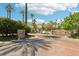 Gated community entrance featuring lush landscaping and palm trees under a bright blue, partially cloudy sky at 2469 Sun Reef Rd, Las Vegas, NV 89128