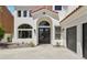 Close up of home's entrance featuring double doors, arched windows, and modern black garage doors at 2469 Sun Reef Rd, Las Vegas, NV 89128