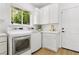 All-white laundry room featuring a window, modern appliances, storage cabinets and gold hardware at 2469 Sun Reef Rd, Las Vegas, NV 89128