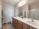 Well-lit bathroom featuring double sinks, a large mirror, and a shower with glass doors at 2473 Luminous Stars St, Henderson, NV 89044