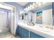 Bright bathroom with double sinks, blue cabinets, and a tub/shower combination at 259 Rockwell Springs Ct, Henderson, NV 89012