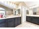Bathroom with tiled floor, marble counters, black cabinets, and decorative lighting at 259 Rockwell Springs Ct, Henderson, NV 89012