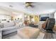 Open-concept living room boasts gray couches, an ottoman, a ceiling fan, and access to the kitchen at 259 Rockwell Springs Ct, Henderson, NV 89012