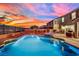 Backyard with a sparkling pool, spa, and ambient lighting, set against a vivid sunset backdrop, perfect for evening relaxation at 2714 Frabiele St, Henderson, NV 89044