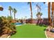 Backyard featuring a refreshing pool, green turf, palm trees, and a privacy wall, perfect for outdoor enjoyment at 286 Bowsprit Ct, Las Vegas, NV 89183