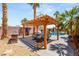 Outdoor patio dining area featuring a wooden pergola, grill, and nearby pool at 286 Bowsprit Ct, Las Vegas, NV 89183