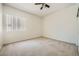 Bright bedroom features a ceiling fan, neutral carpet and a window with vertical blinds at 324 Quiet Harbor Dr, Henderson, NV 89052