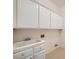 Laundry room boasts upper cabinets and a utility sink with tile backsplash at 324 Quiet Harbor Dr, Henderson, NV 89052