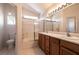 Well-lit bathroom featuring a double sink vanity, bathtub and shower with glass doors, and a toilet at 4439 Scarlet Sea Ave, North Las Vegas, NV 89031