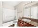 Bathroom featuring a wooden vanity with a granite countertop and tub with white tile at 6800 E Lake Mead Blvd # 1018, Las Vegas, NV 89156