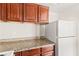 Kitchen area featuring granite countertops, wooden cabinets, and a white refrigerator at 6800 E Lake Mead Blvd # 1018, Las Vegas, NV 89156