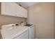 Convenient laundry room with white washer and dryer and upper cabinet storage at 7488 Evening Falls Dr, Las Vegas, NV 89131