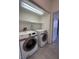 Convenient laundry room featuring modern, front-loading washer and dryer units with shelving for storage at 8042 Palace Monaco Ave, Las Vegas, NV 89117