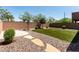 Landscaped backyard featuring artificial turf, trees, rock ground cover, a brick wall, and stepping stones at 1034 Fish Pond Ave, Henderson, NV 89014
