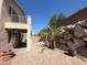 Backyard area with paver pathway, rock wall, palm trees, and second story balcony at 1177 Twinkling Meadows Dr, Henderson, NV 89012
