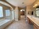 Bright bathroom featuring a soaking tub, a glass shower and a dual sink vanity at 1177 Twinkling Meadows Dr, Henderson, NV 89012