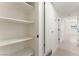 Hallway with an open shelved linen closet with light-colored wood floors and doors that have black hardware at 2854 La Canada St, Las Vegas, NV 89169