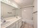Bathroom with a double sink vanity, tiled floor, and shower/tub with white tile surround at 4010 Hemphill St, North Las Vegas, NV 89032