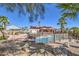 Home's backyard shows pool, covered patio, palms, desert landscaping, and solar panels on the roof at 4010 Hemphill St, North Las Vegas, NV 89032