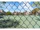 Community tennis court featuring a green court surface, chain-link fencing, and condo buildings at 5038 S Rainbow Blvd # 206, Las Vegas, NV 89118