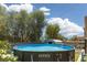A blue above ground pool surrounded by trees under a partly cloudy sky at 5620 Siena Rose St, North Las Vegas, NV 89031