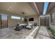 This covered patio includes modern furniture, a ceiling fan, a mounted TV, and views of the landscaped yard at 6804 Regency Stone Way, Las Vegas, NV 89148