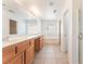 Bright bathroom with double sink vanity, large mirror, soaking tub, and tiled floors offering a clean and modern aesthetic at 7553 Virginia Dale St, Las Vegas, NV 89131