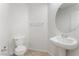 Cozy powder room featuring a pedestal sink, round mirror and tiled flooring at 7553 Virginia Dale St, Las Vegas, NV 89131
