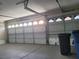 The interior of a clean garage featuring a white garage door, gray floor and storage bins at 9556 Ancala Hollow Ct, Las Vegas, NV 89148
