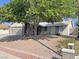 Single-story home featuring a two-car garage, mature trees, and rock landscaping at 1441 Bronco Rd, Boulder City, NV 89005