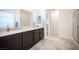 Bathroom featuring double sinks with granite countertops, dark cabinets, and a glass-enclosed shower at 1617 Meadow Bluffs Ave, Henderson, NV 89014