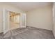 Cozy living room featuring neutral walls, plush carpet, and open door leading to stairs at 1633 Dornie Ave, North Las Vegas, NV 89084