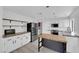 Modern white kitchen with black stainless appliances, an island, and a tile backsplash at 21 Rue De Degas, Henderson, NV 89074