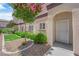Exterior side view of a condo featuring a decorative front door, rock garden, and pink flowering tree at 2291 W Horizon Ridge Pkwy # 6131, Henderson, NV 89052