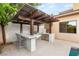 Outdoor kitchen with a built-in grill, bar seating, and a stylish pergola for shade and ambiance at 38 Moonfire Dr, Las Vegas, NV 89135