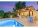 Covered outdoor kitchen boasts a built-in grill and bar seating next to the pool at 38 Moonfire Dr, Las Vegas, NV 89135
