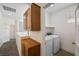 Hallway laundry space with wooden cabinets above washer and dryer at 4351 Hera Temple Ave, North Las Vegas, NV 89031
