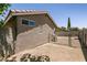 Backyard with stone wall and chain link fence enclosing a graveled area, accented with greenery at 4825 White Aspen Ave, Las Vegas, NV 89130