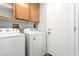 Well-lit laundry room featuring a washer, dryer, overhead cabinets, and a convenient utility door at 6112 Grape Blossom Ave, Las Vegas, NV 89142
