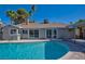 Sun-drenched backyard showcasing a sparkling pool with clear blue water, flanked by palm trees and lush landscaping at 6848 Groveview Ln, Las Vegas, NV 89103