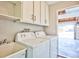 Bright laundry area with washer, dryer, utility sink, white cabinets, and a view of the garage at 6848 Groveview Ln, Las Vegas, NV 89103