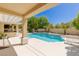 Inviting pool area with a covered outdoor kitchen, seating, and lush landscaping creates a perfect backyard oasis at 712 Proud Eagle Ln, Las Vegas, NV 89144